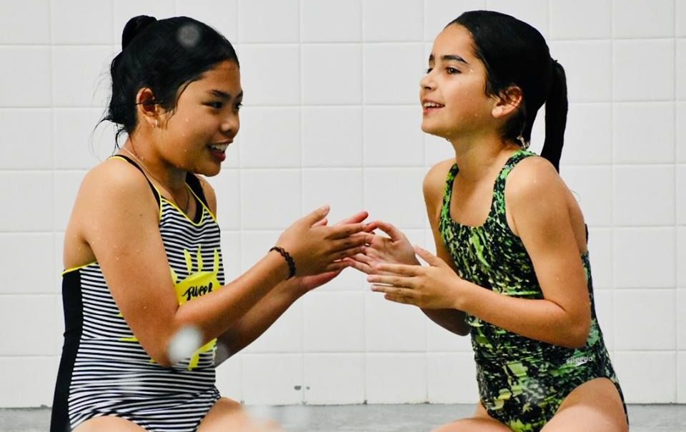 A group of children are swimming in a swimming pool.