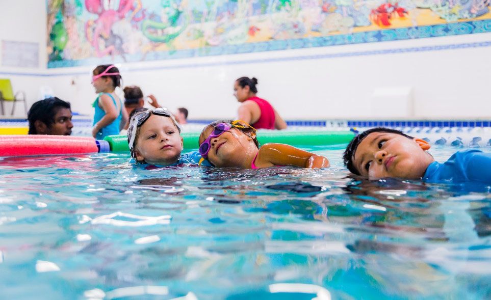 A group of children are swimming in a swimming pool.