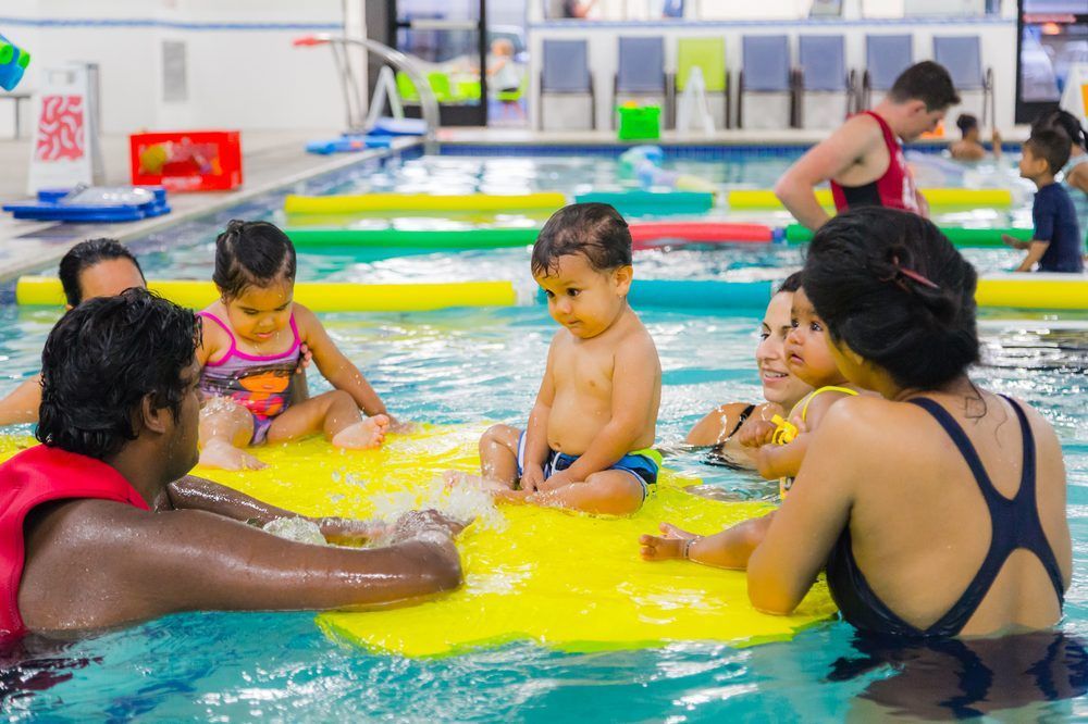 A group of people are sitting on rafts in a swimming pool.