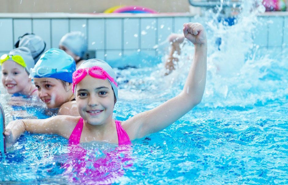 A group of children are swimming in a swimming pool.