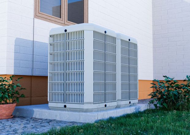 A large air conditioner is sitting on the side of a house.