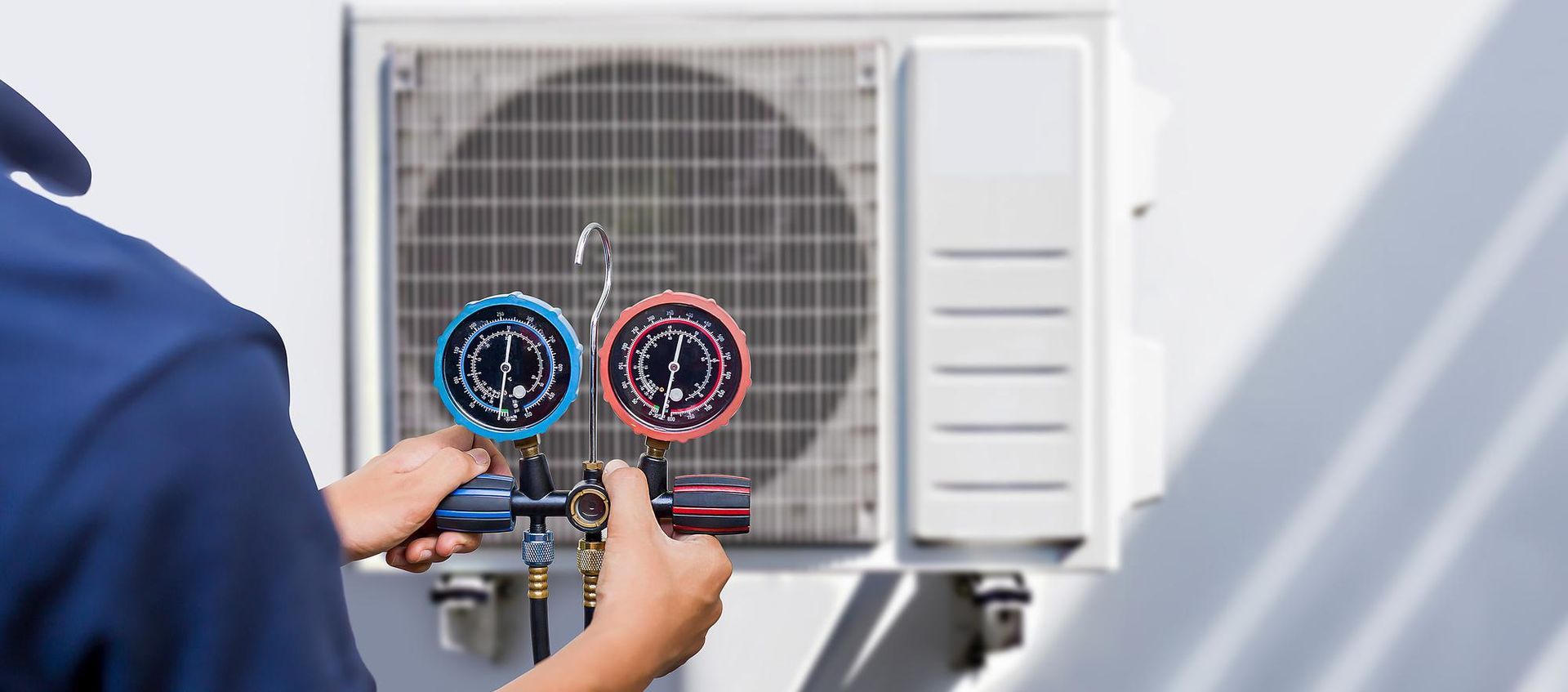 A man is working on an air conditioner outside of a building.