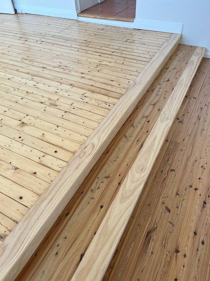 A close up of a wooden floor with stairs in a room.