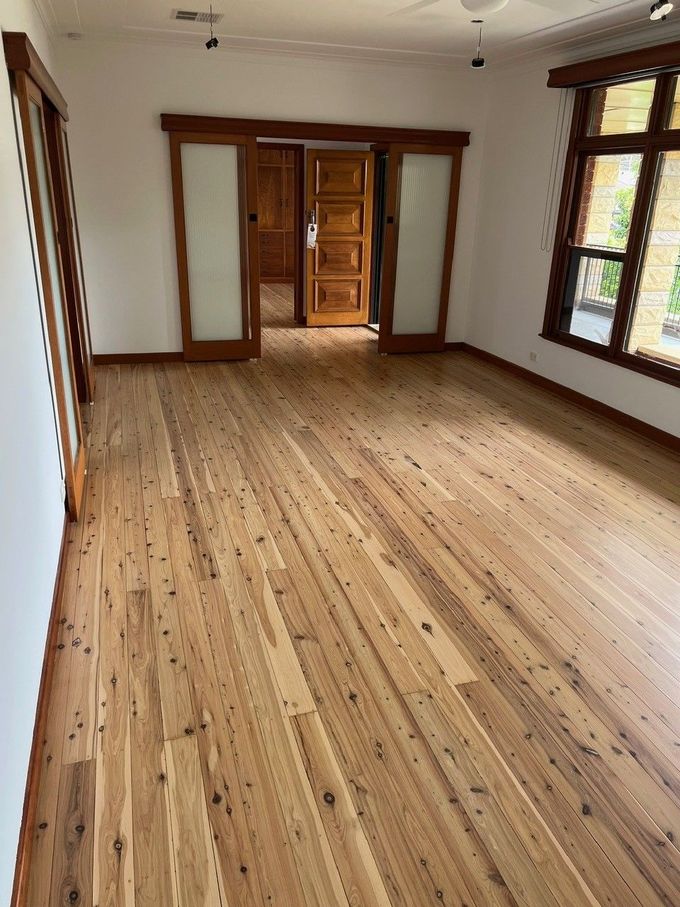 An empty room with a wooden floor and sliding glass doors.