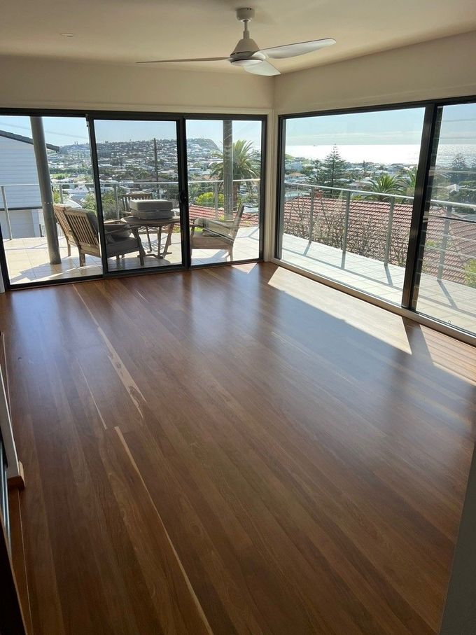 A living room with hardwood floors , sliding glass doors , a ceiling fan and a balcony.