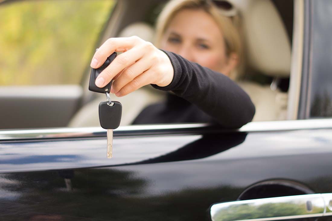 A woman is holding a car key in her hand while sitting in a car.