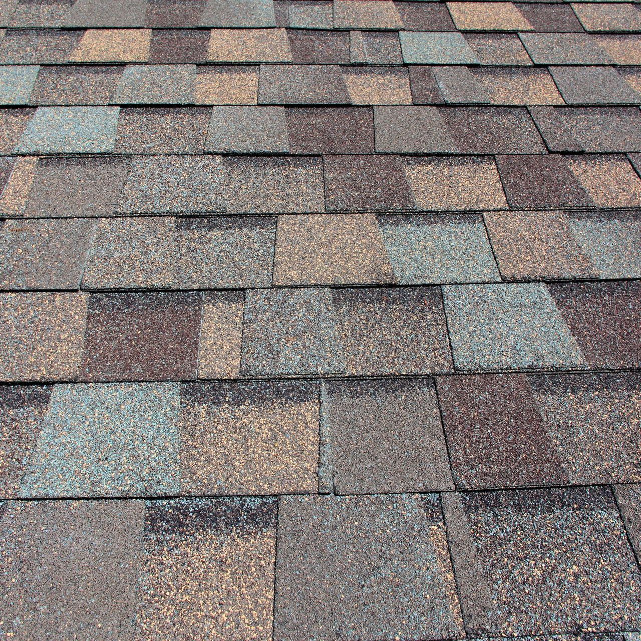 A close up of a roof with multi color shingles on it