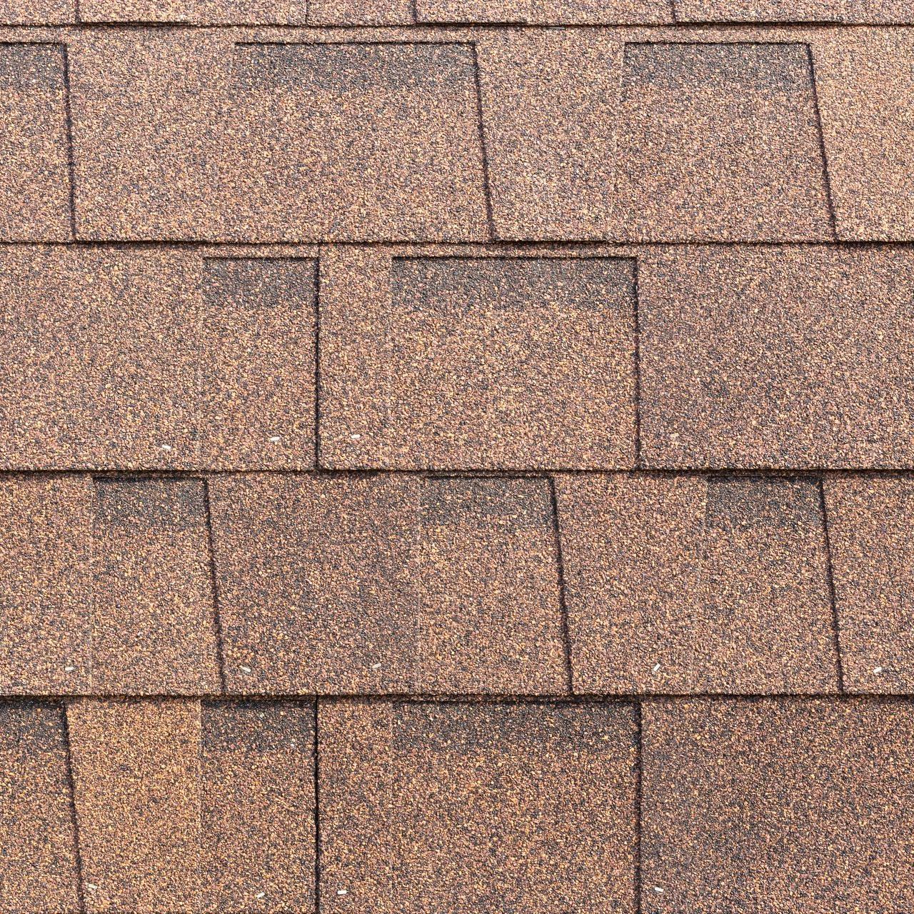A close up of a roof with brown shingles