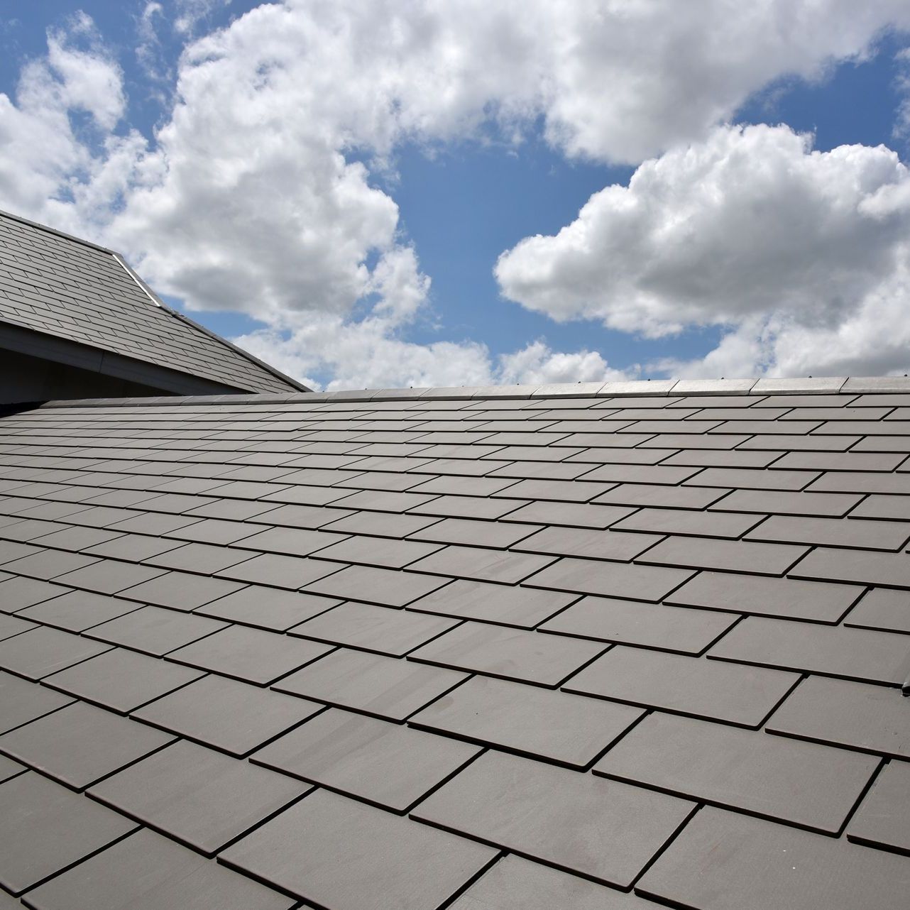 A roof with a blue sky and clouds in the background
