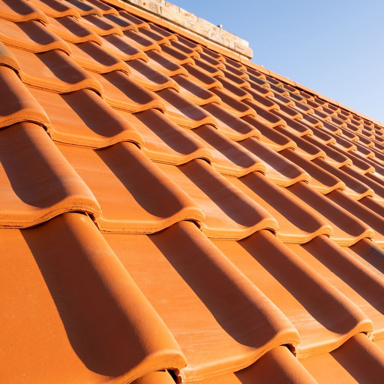 A close up of a tiled roof with a blue sky in the background