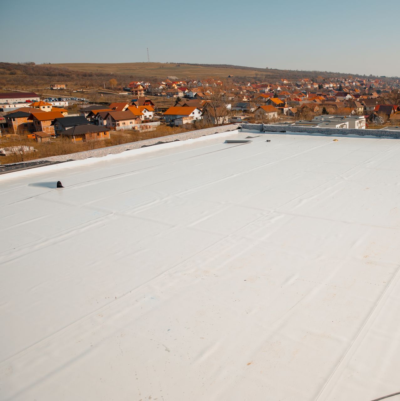 An aerial view of a flat white roof with a small town in the background