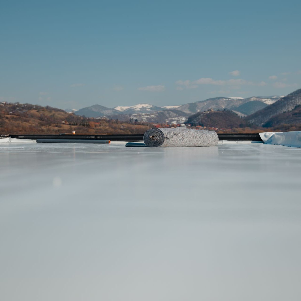 A roller is sitting on top of a white surface with mountains in the background.