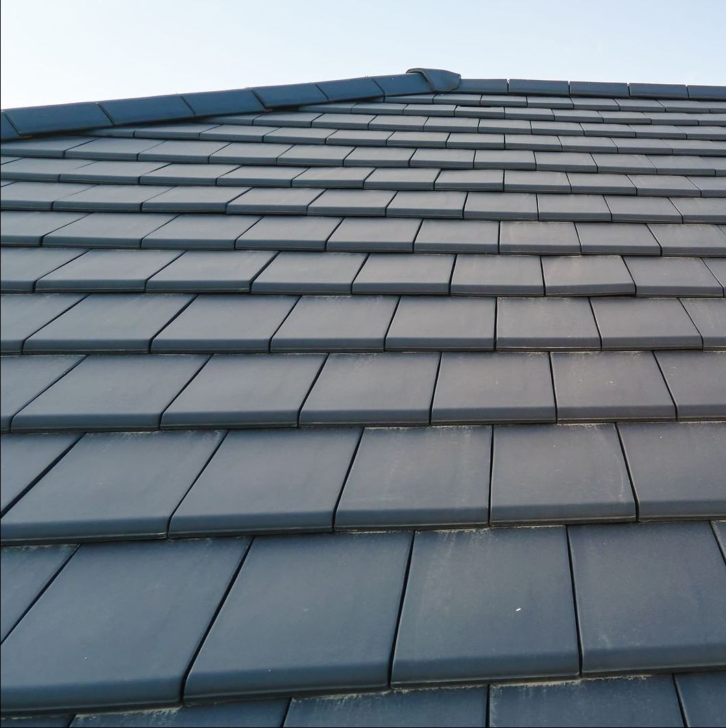 A close up of a slate roof with a blue sky in the background