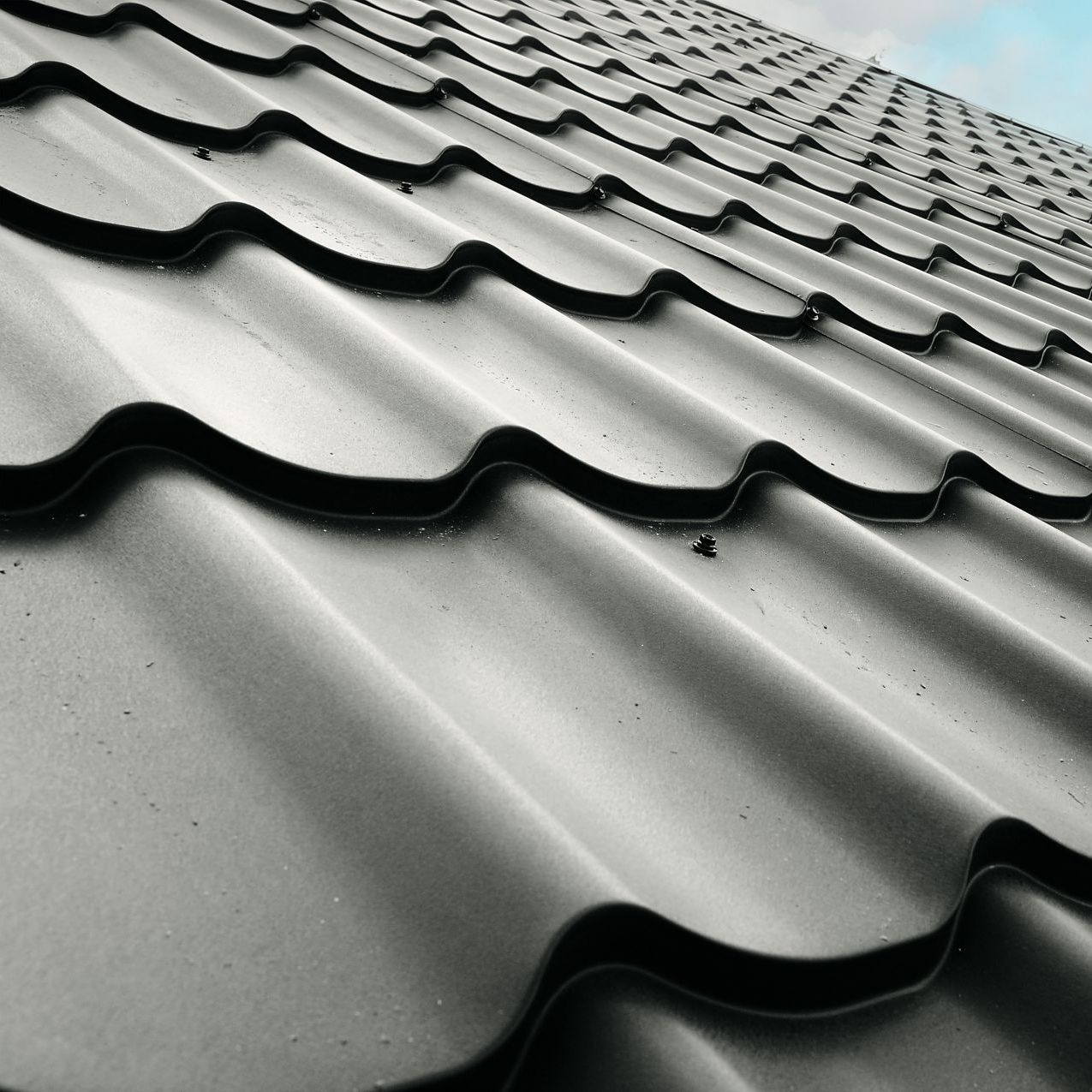 A close up of a tile roof with a blue sky in the background