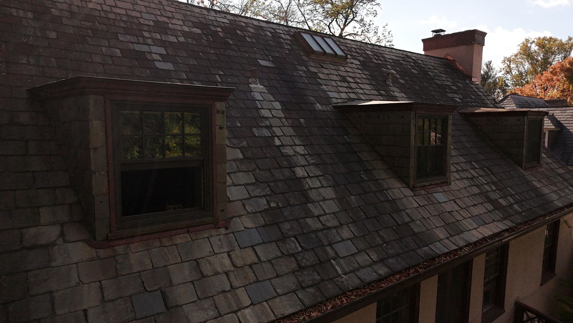 A old roof with damaged tiles and dormer windows
