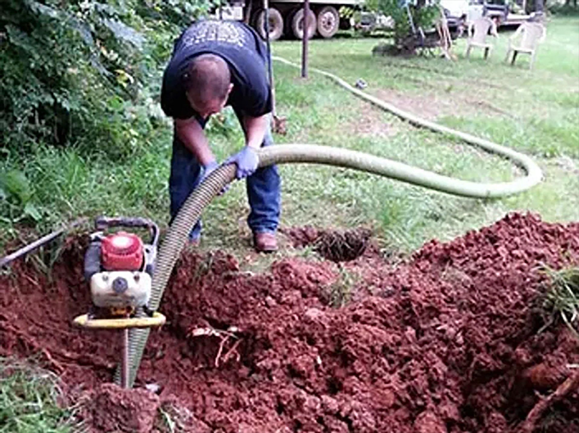 A man is pumping water into a hole in the ground.