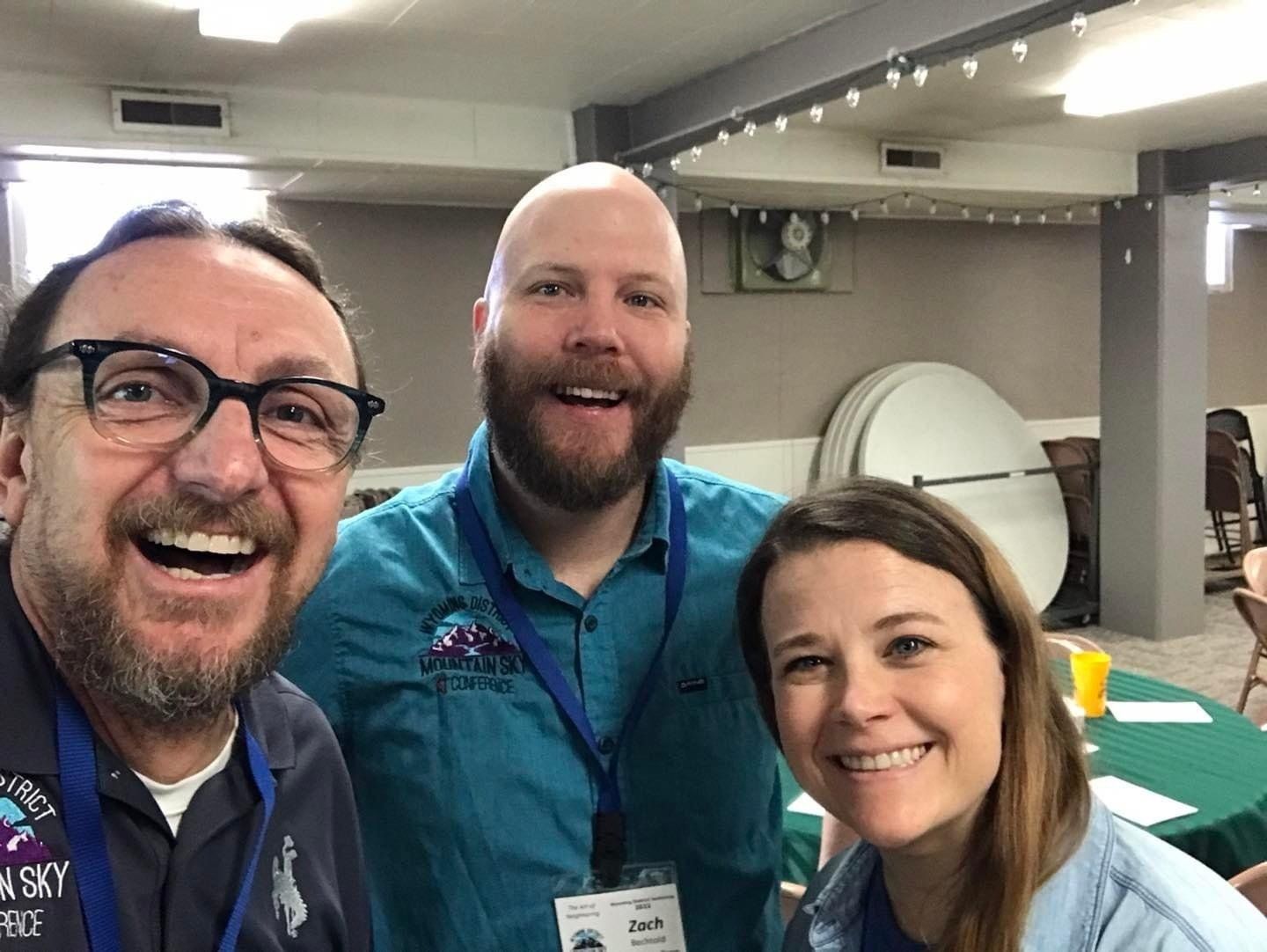 Three people are posing for a picture in a room and smiling.