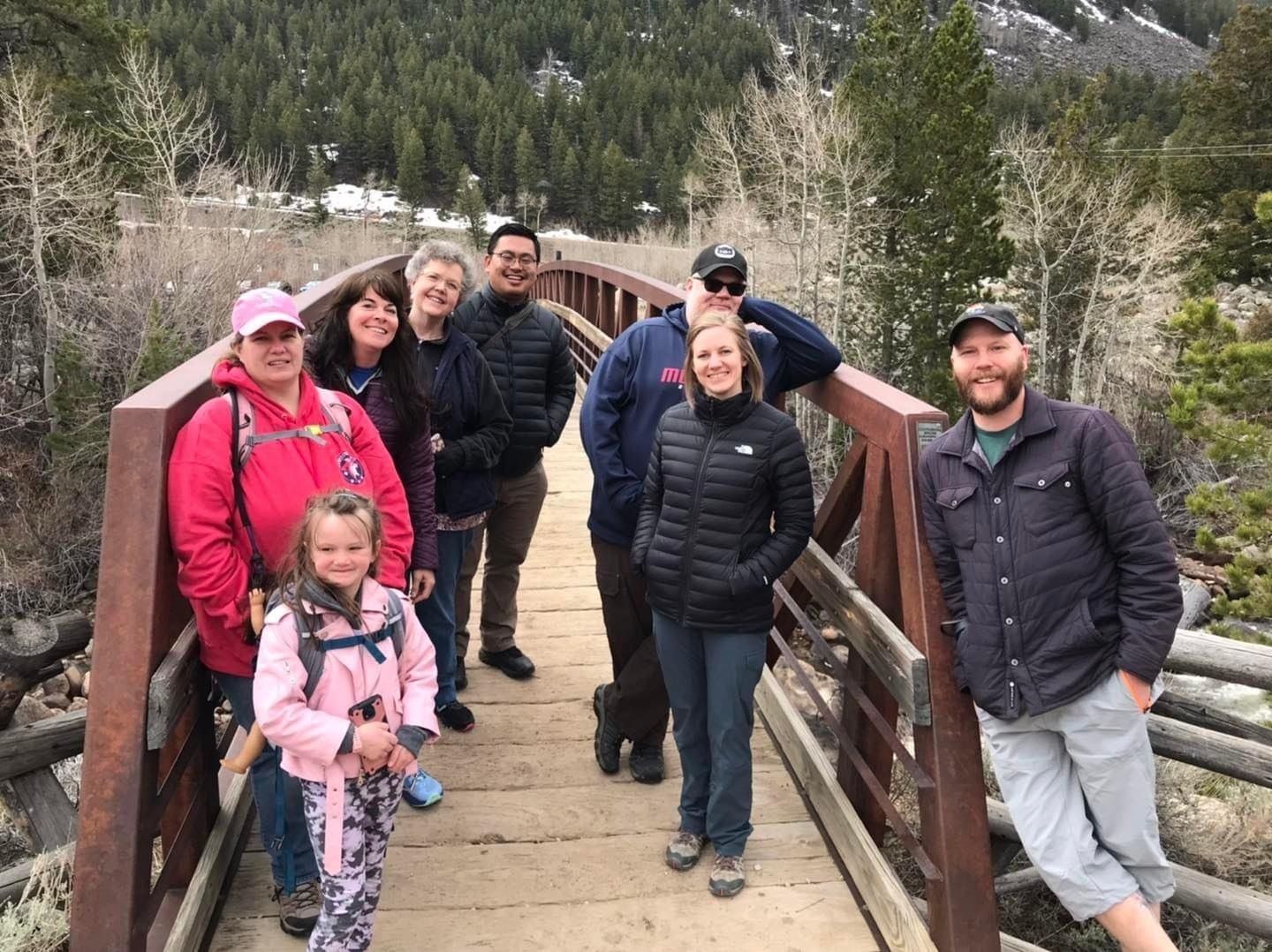 A group of people are standing on a wooden bridge.