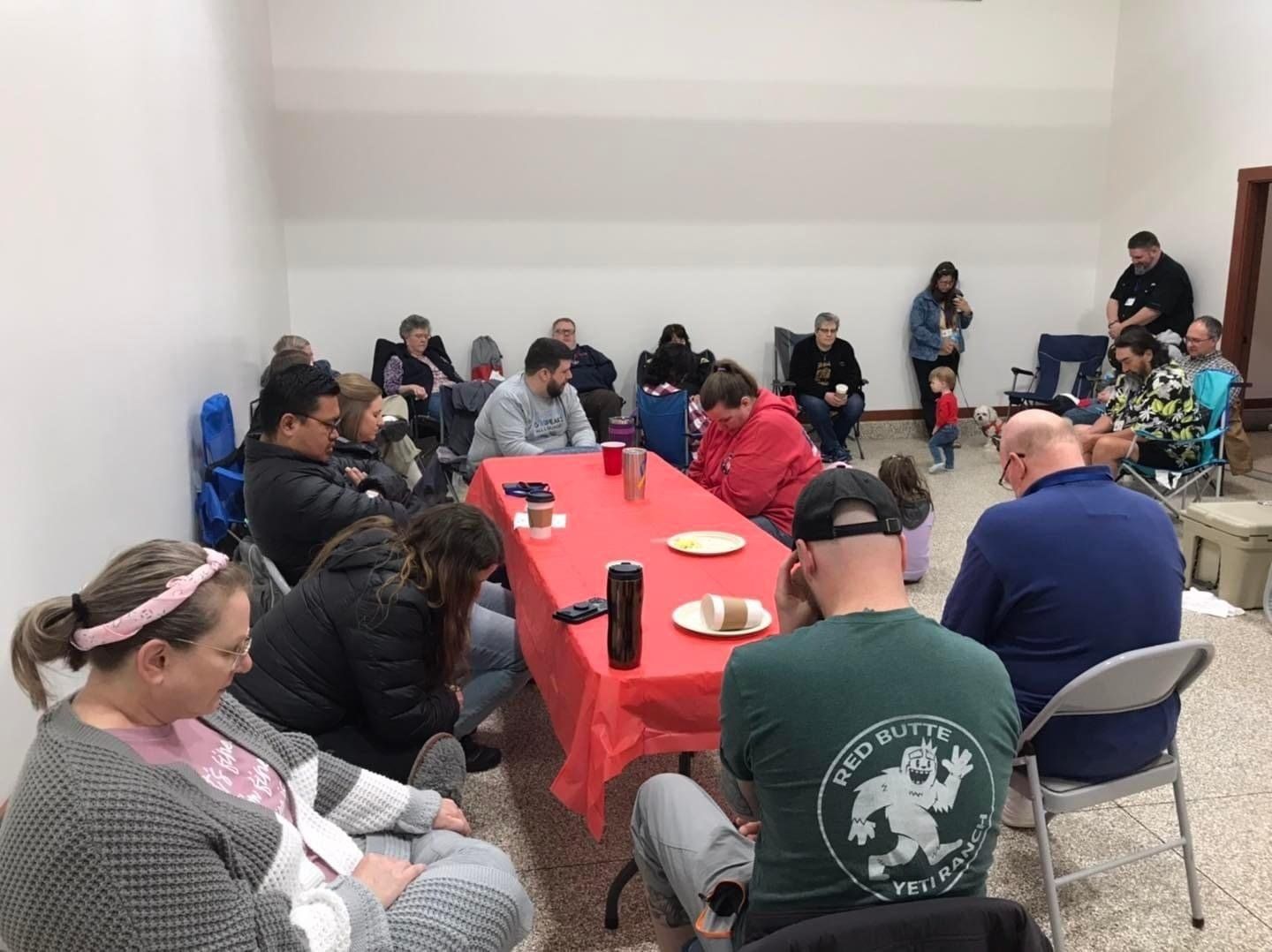 A group of people are sitting around a long table in a room.