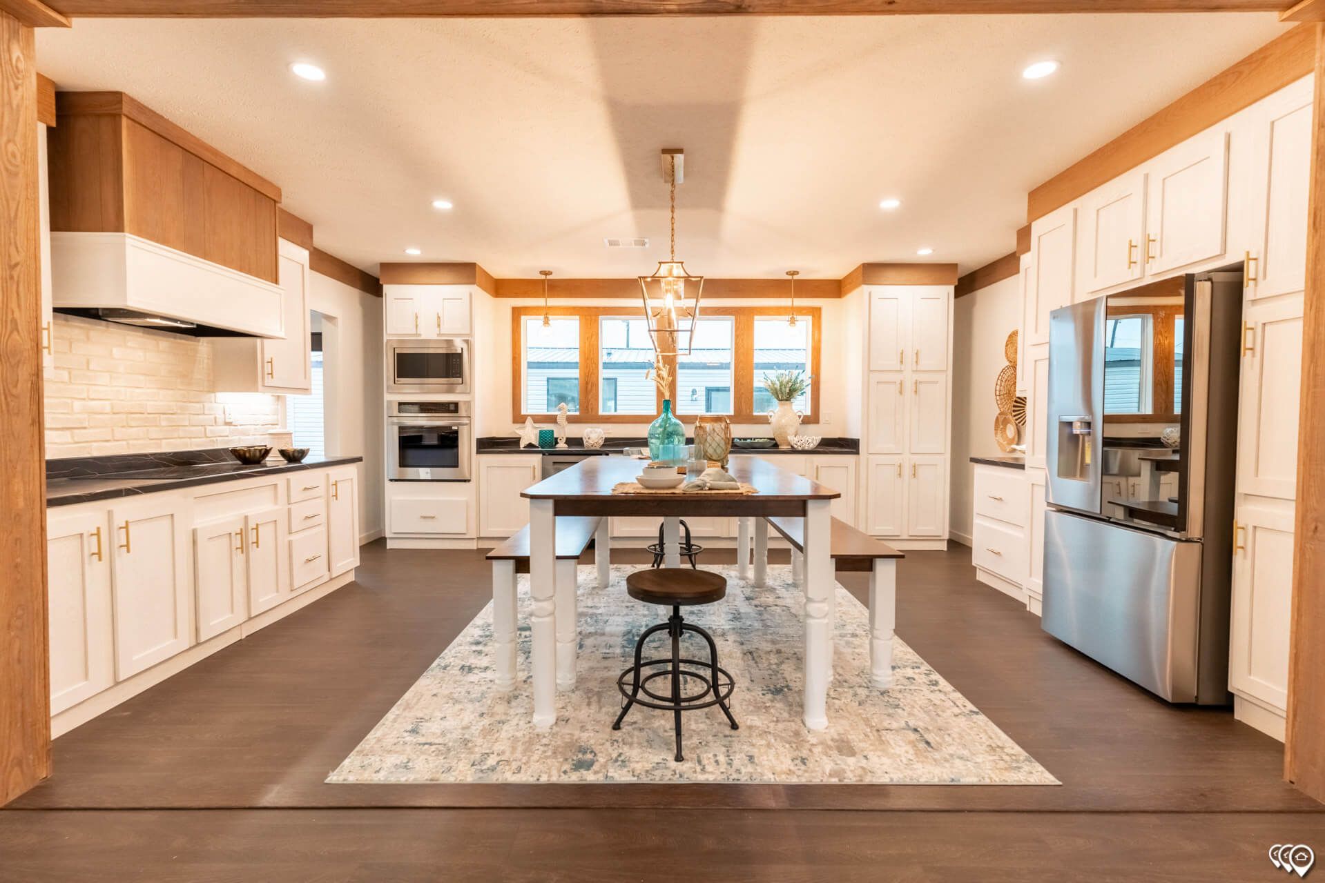 A kitchen with white cabinets , stainless steel appliances , a table and benches.