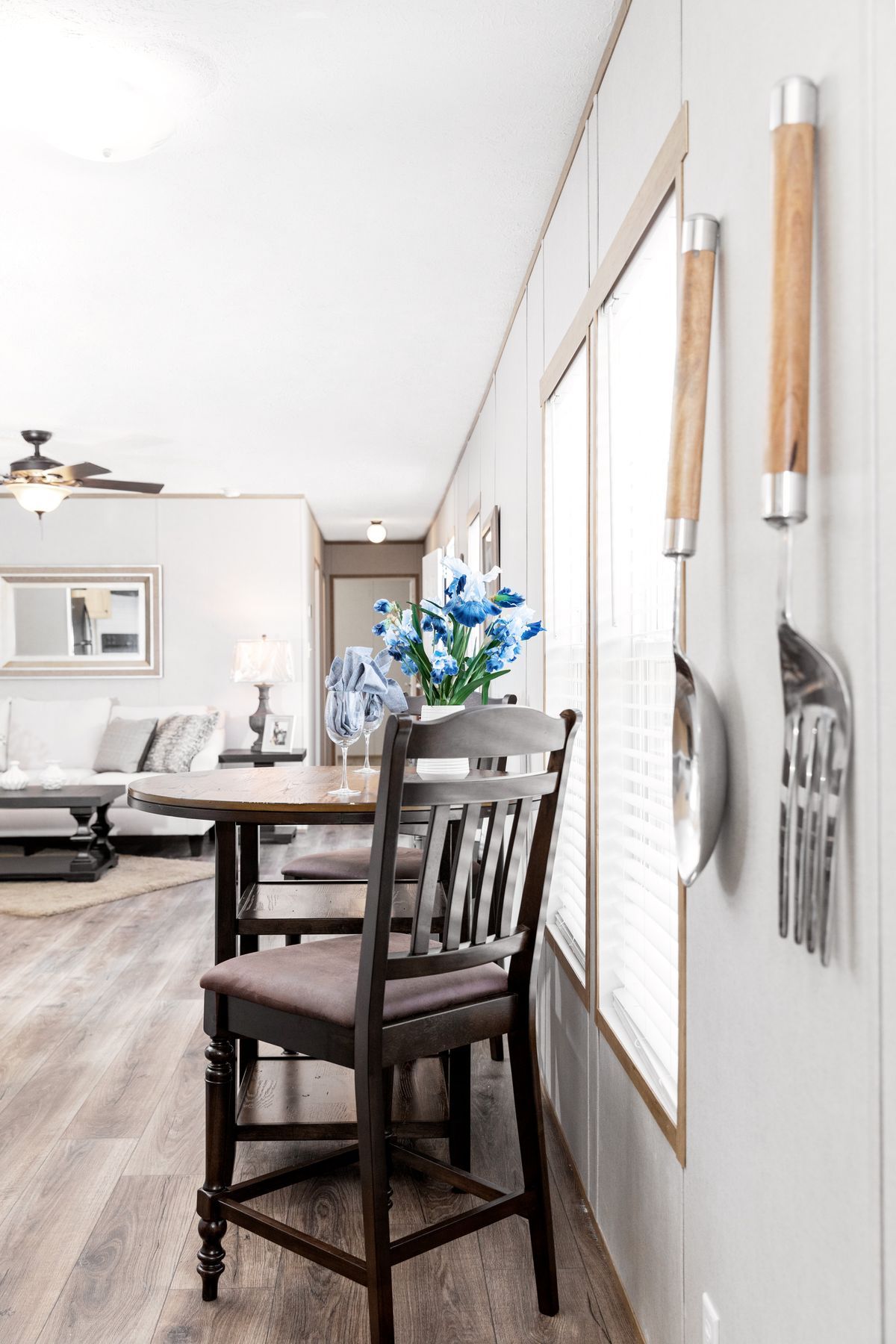 A dining room with a table and chairs and utensils hanging on the wall.