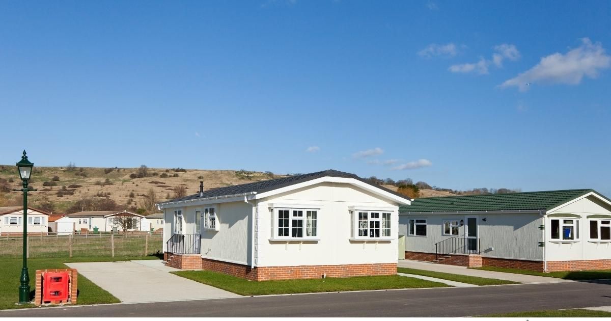 Mobile homes on a sunny day, set against a hillside under a blue sky.