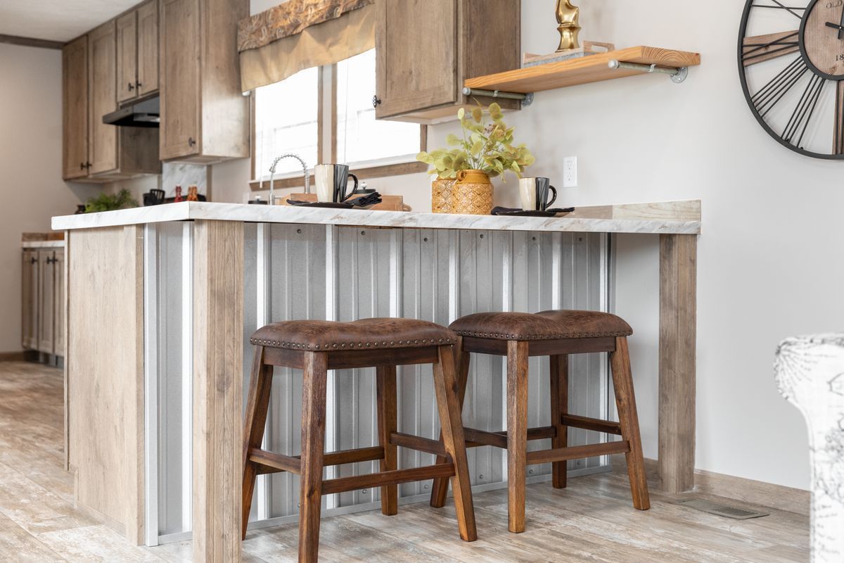 A kitchen with a bar and stools and a clock on the wall.