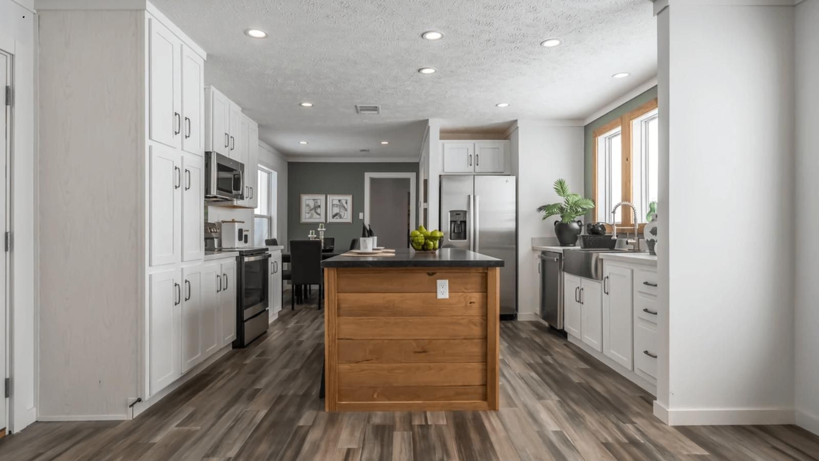 A kitchen with white cabinets and a wooden island in the middle.