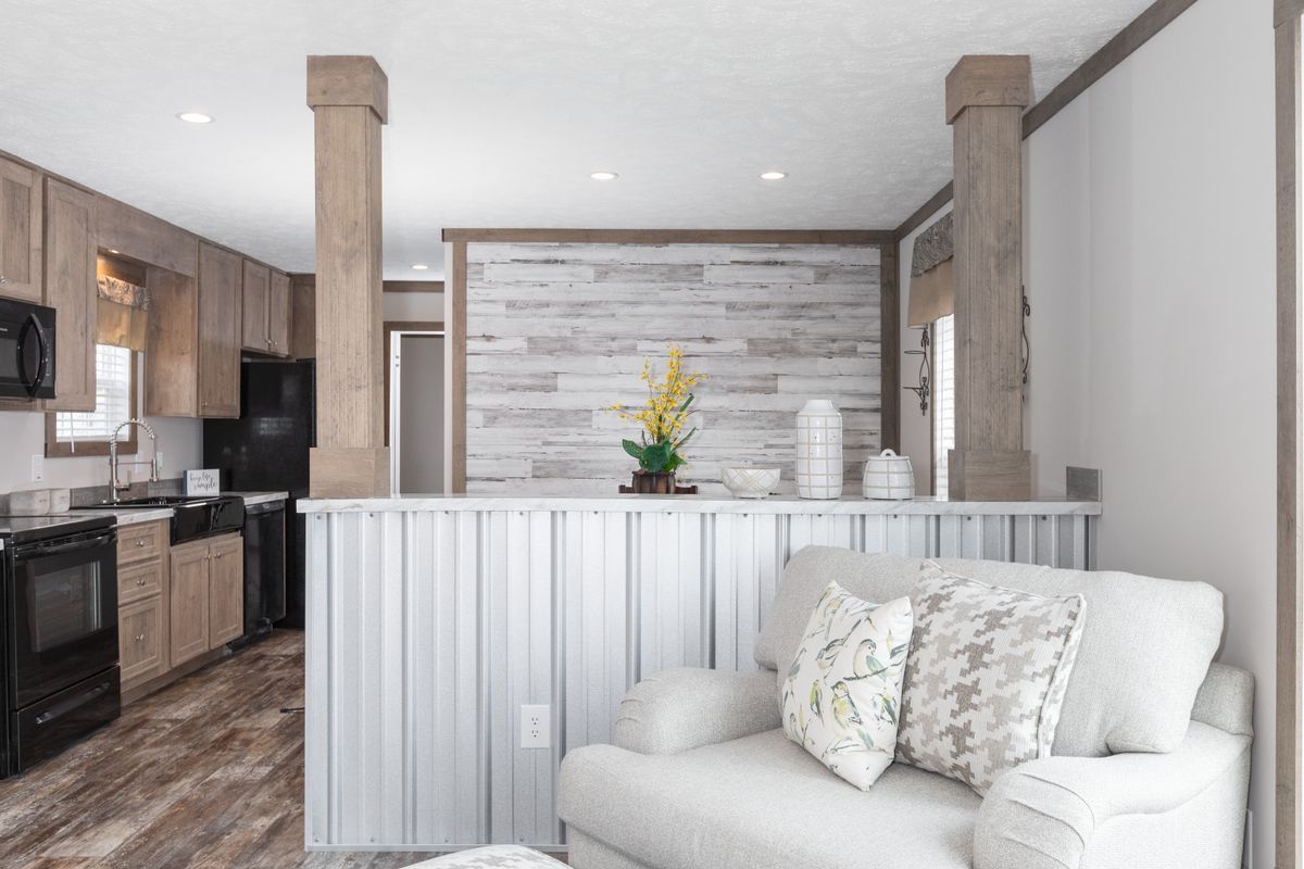 A living room with a couch , chair , and a kitchen.