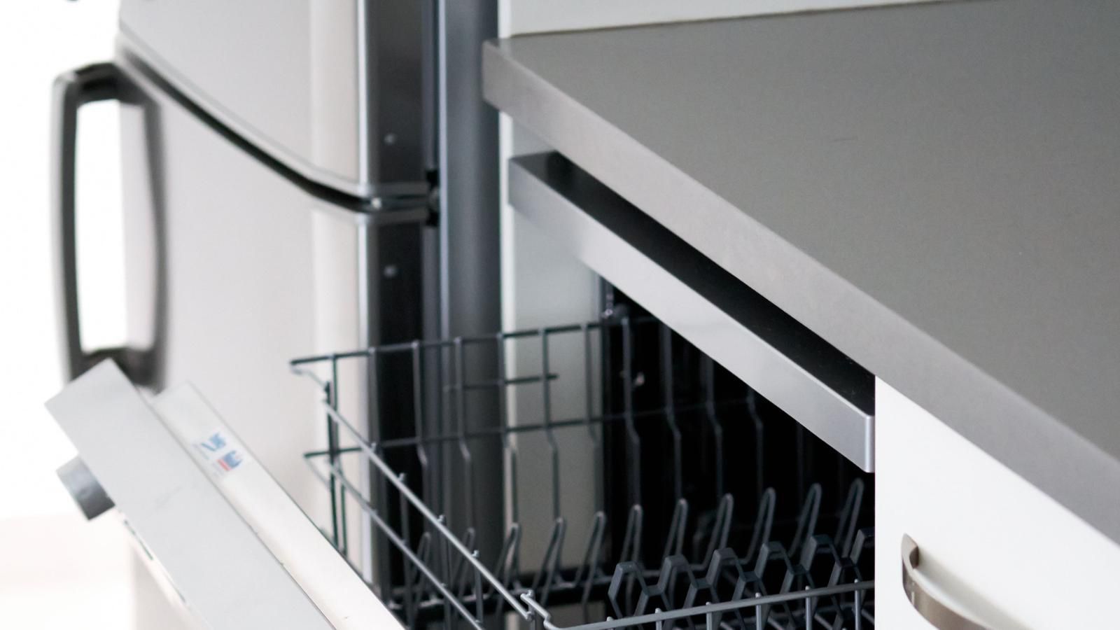 A dishwasher is open in a kitchen next to a refrigerator