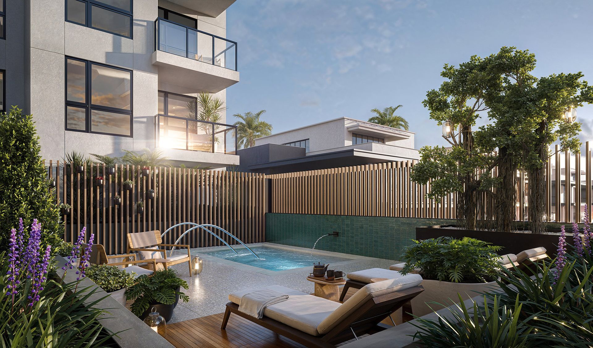 Luxury outdoor spa area with lounge chairs, foliage, and a modern building in the background.