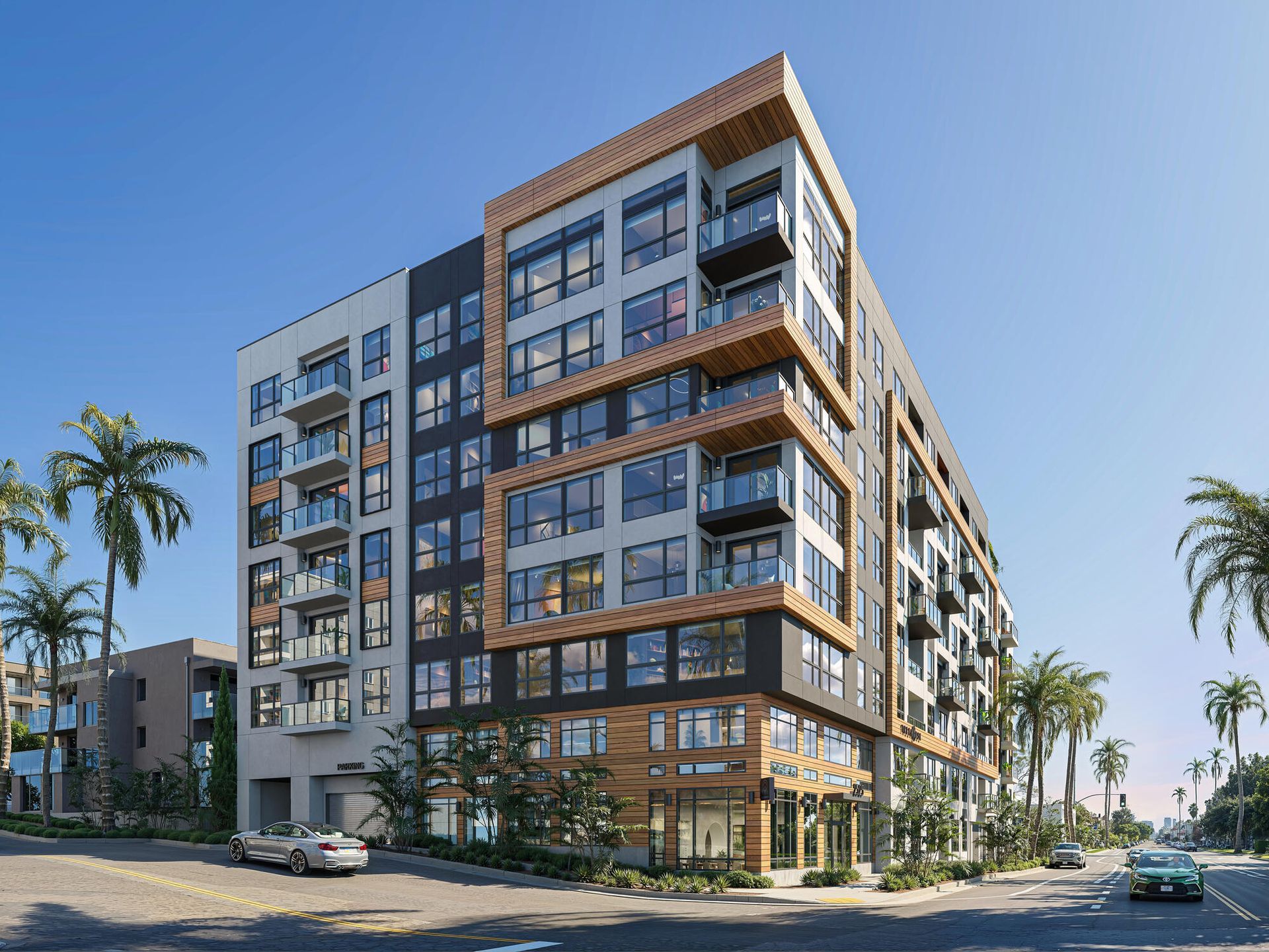 Modern multi-story apartment building with balconies, gray, black, and wood accents, palm trees, and parked cars.