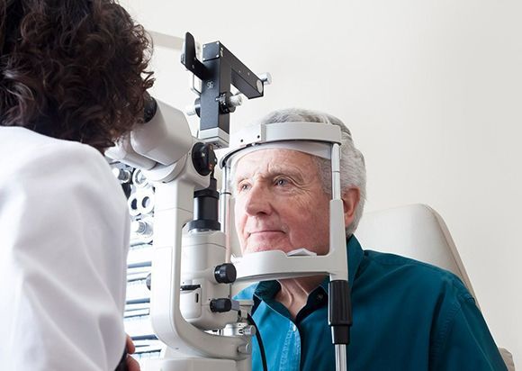 Optometrist giving eye exam to senior patient — Munster, IN — Munster Eye Care Associates