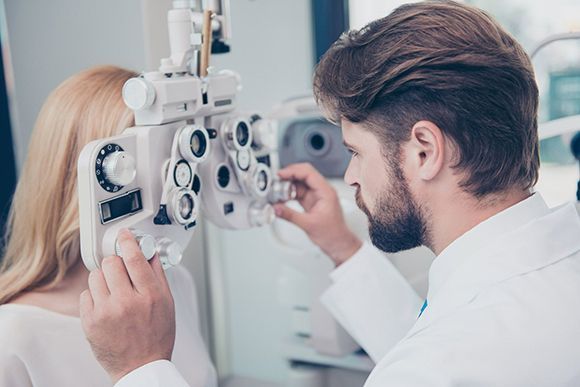 Optometrist adjusting phoropter — Munster, IN — Munster Eye Care Associates