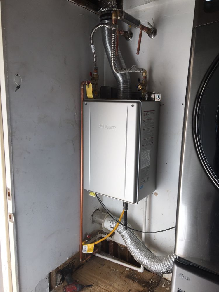 A water heater is sitting in a laundry room next to a washer and dryer.