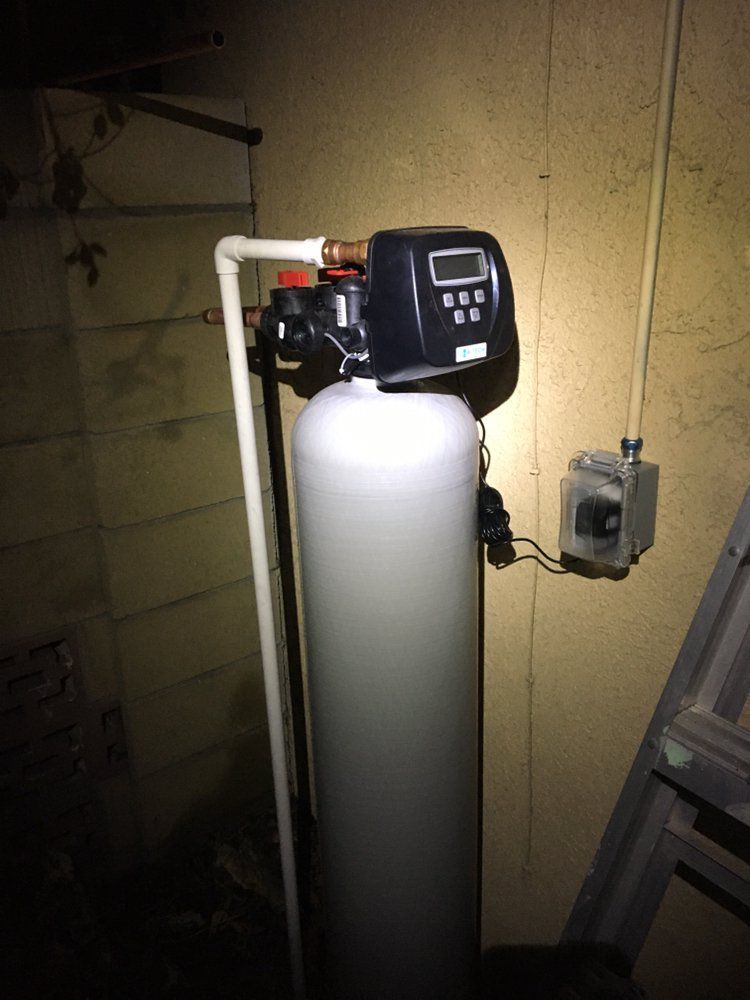 A water filter is sitting in a dark room next to a ladder.