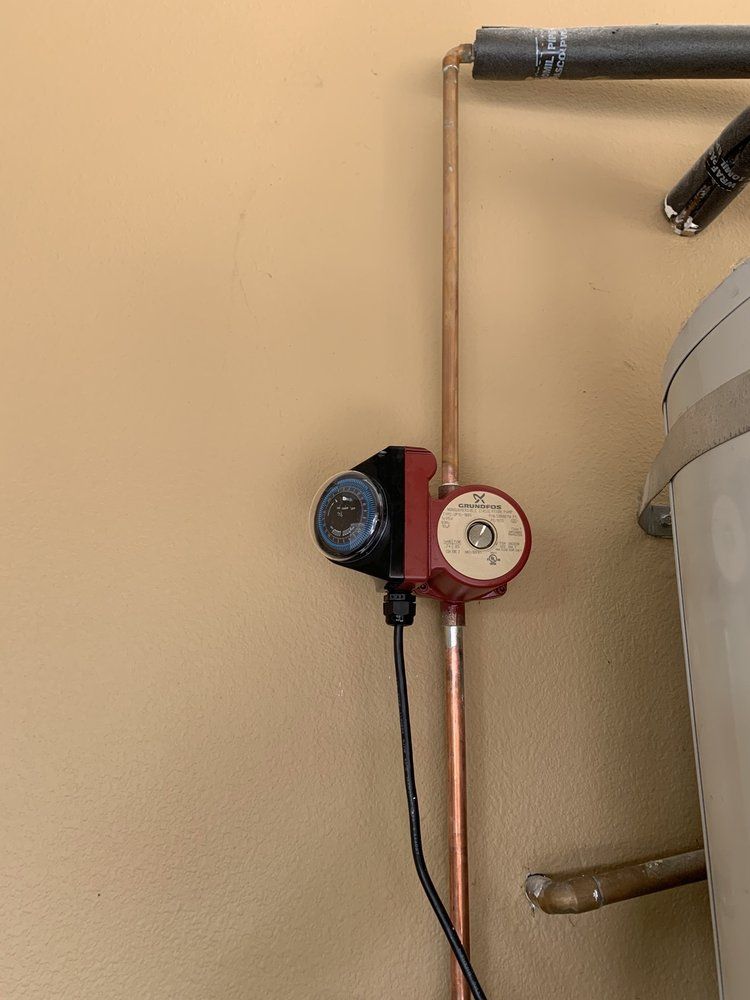 A water pump is attached to a copper pipe on a wall.