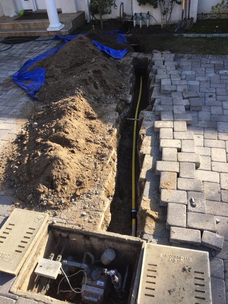 A large pile of dirt is sitting in the middle of a brick driveway.