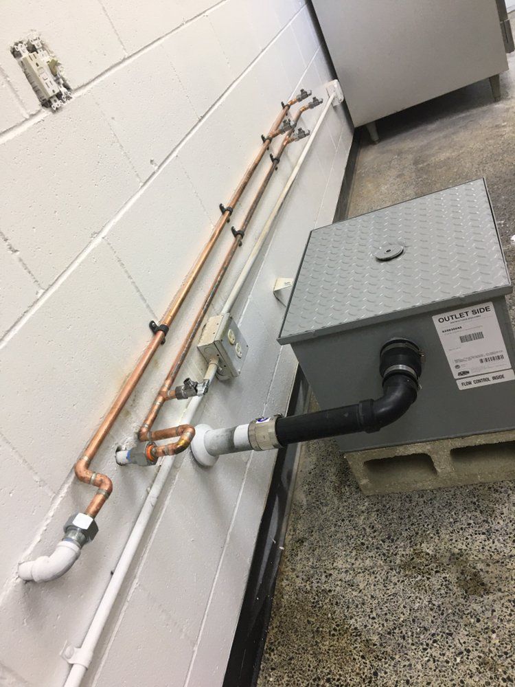 A copper pipe is connected to a metal box on a wall.