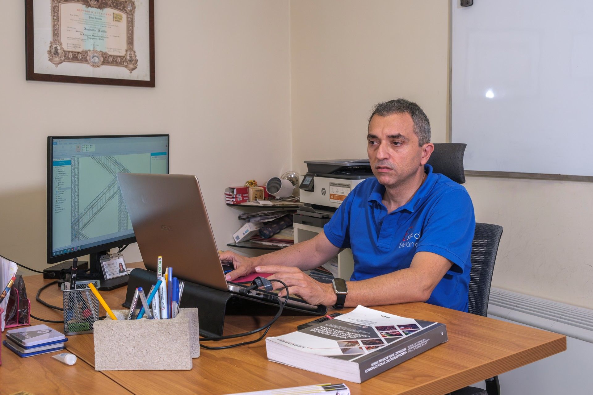 Un uomo è seduto alla scrivania e utilizza un computer portatile.