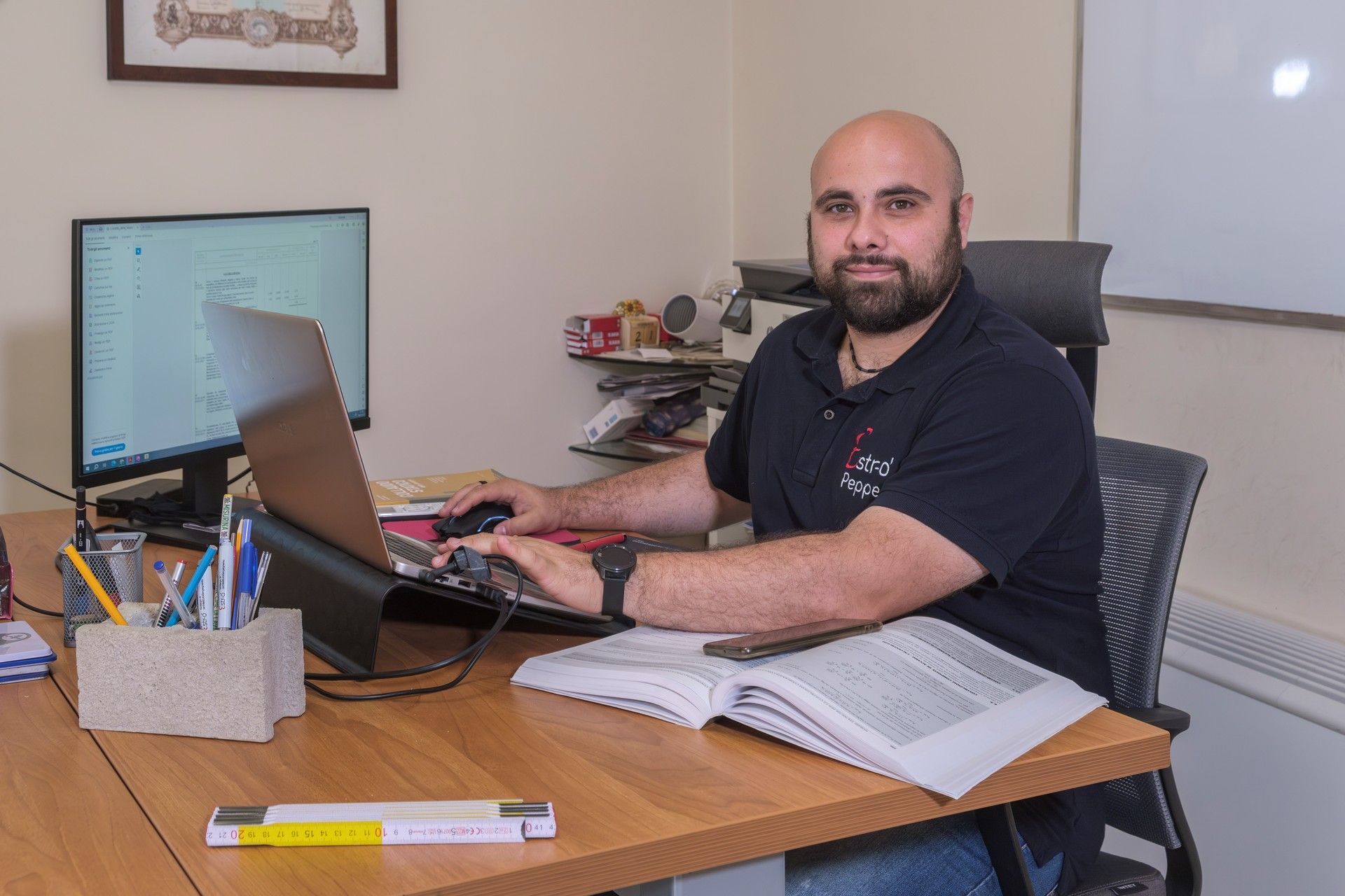 Un uomo è seduto alla scrivania e utilizza un computer portatile.