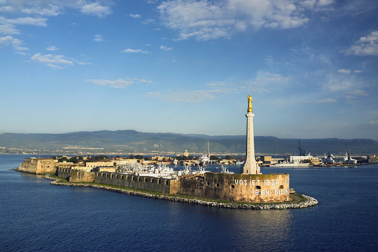 Una piccola isola con una statua sopra in mezzo all'oceano.
