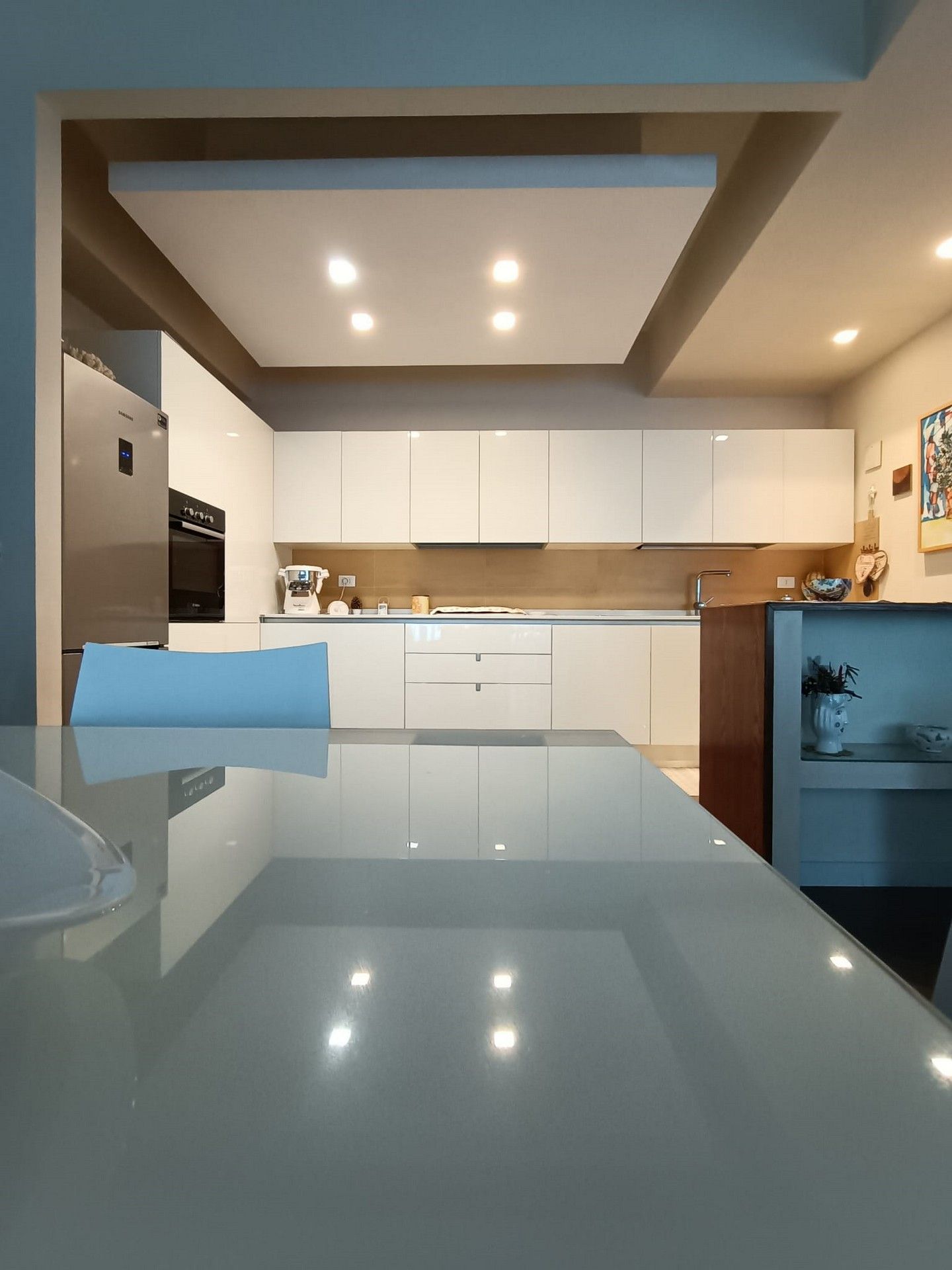 Una cucina con mobili bianchi e un frigorifero in acciaio inossidabile