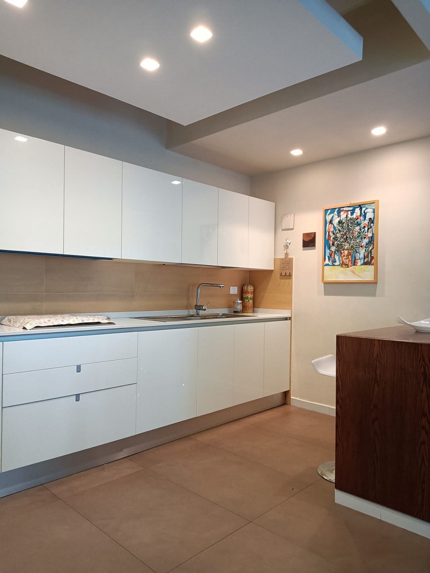 Una cucina con mobili bianchi e un dipinto sul muro