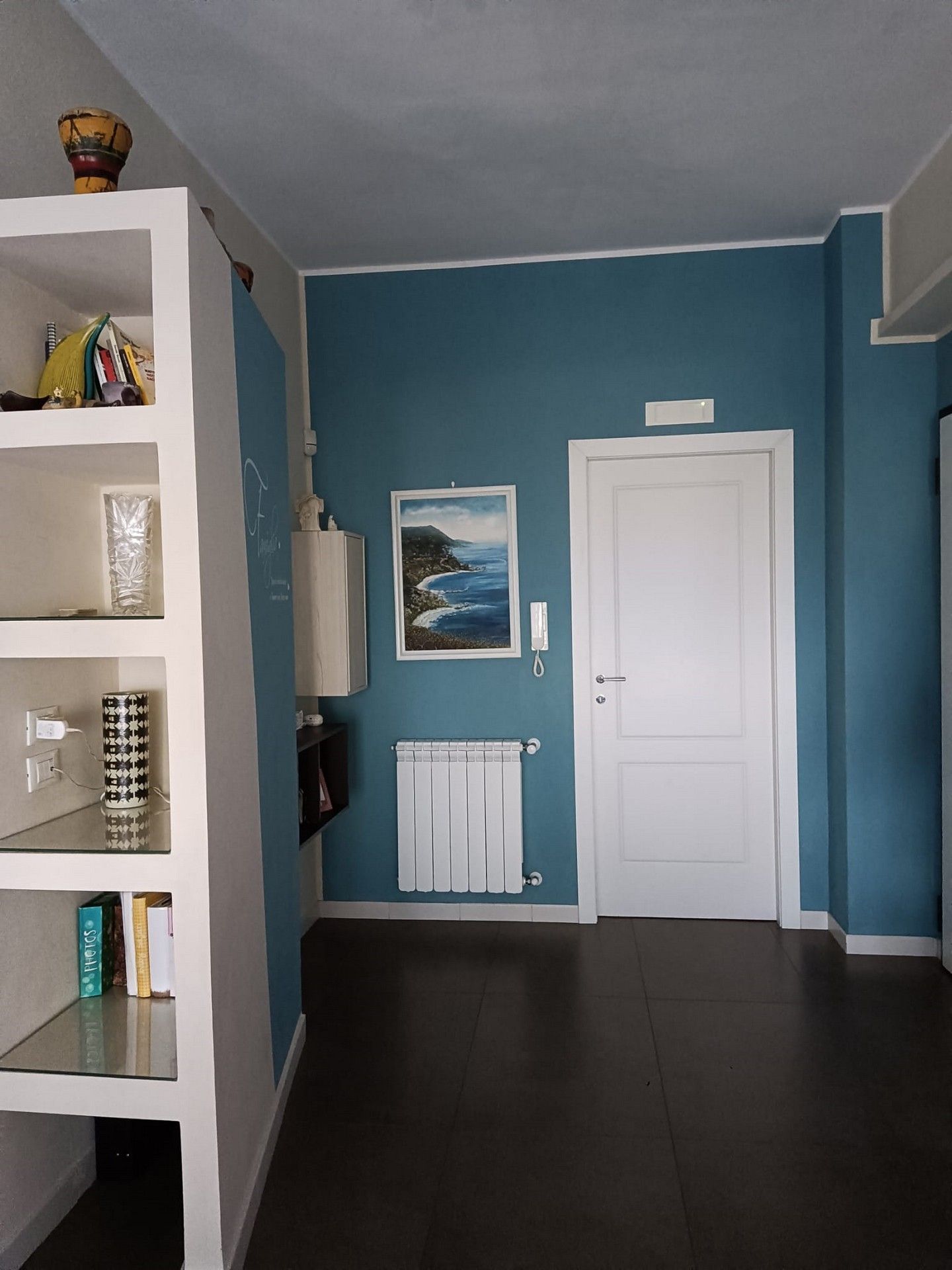 Un corridoio con pareti blu e una porta bianca