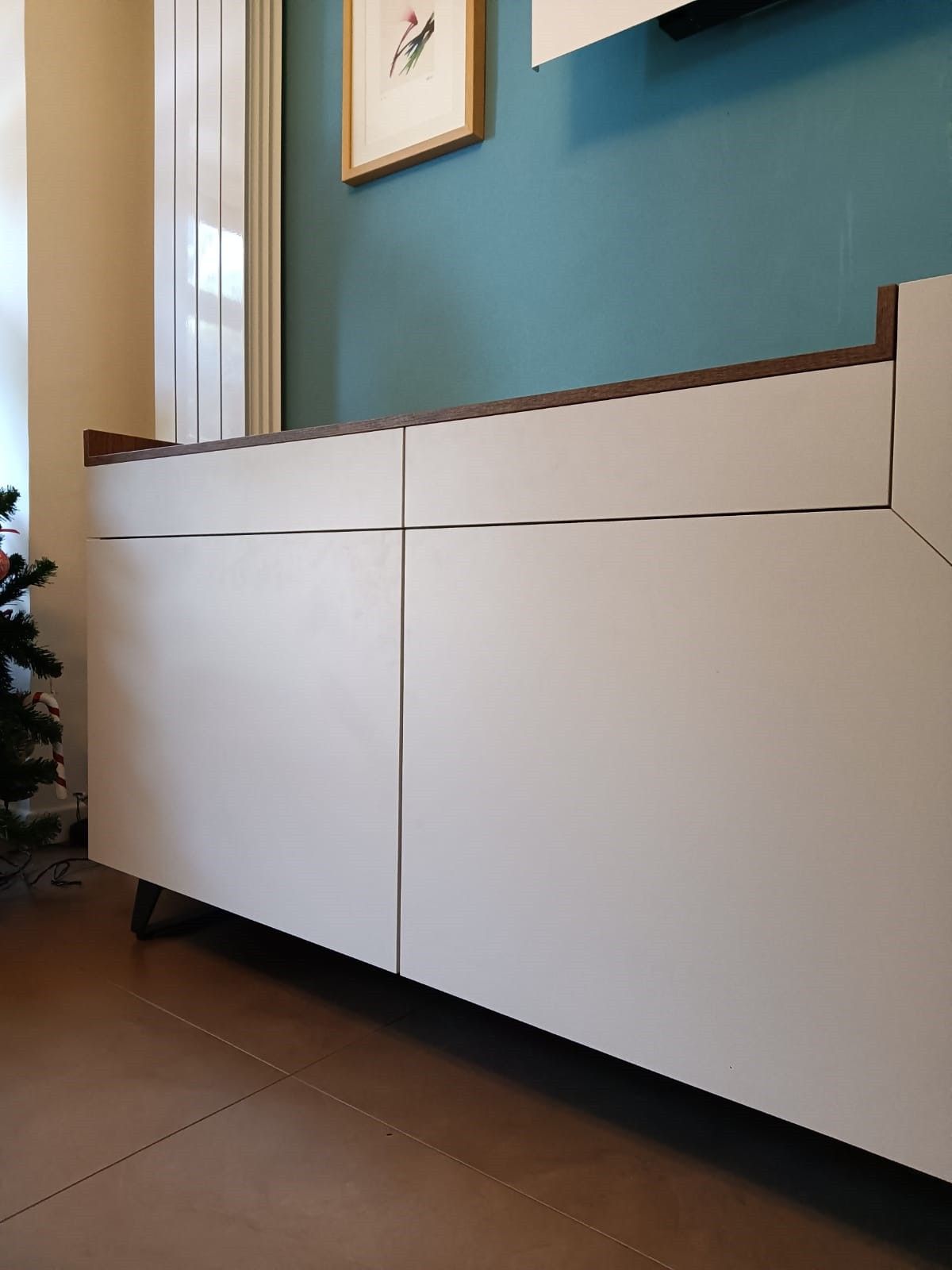 Un mobile bianco con cassetti e un albero di Natale sullo sfondo.