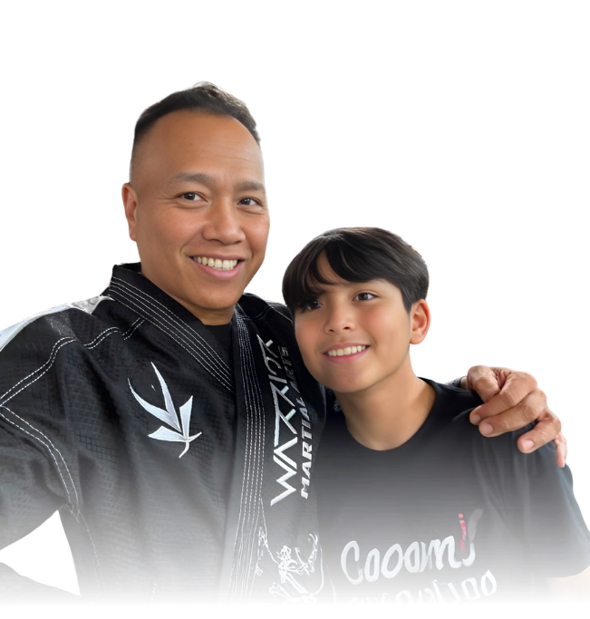 Man pointing, smiling, wearing black hoodie; arm tattoo visible.