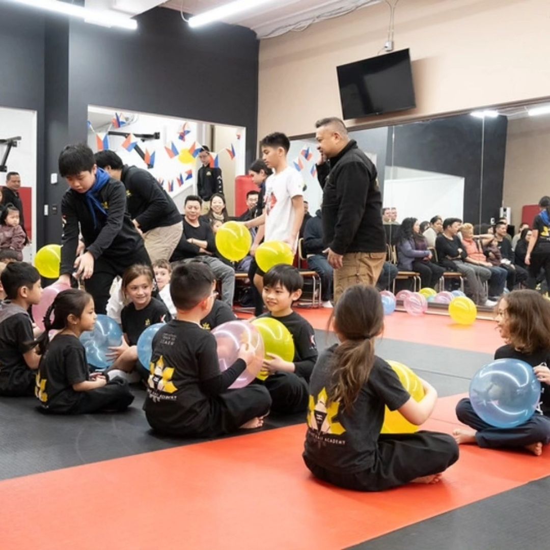 Two children grappling on a mat, one in a headlock.