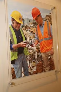 Two workers in hard hats examine debris at a construction or demolition site.