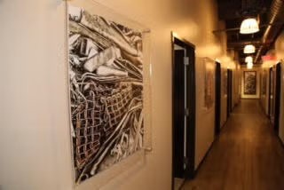 Warm-lit hallway with framed abstract artwork and doors along the corridor